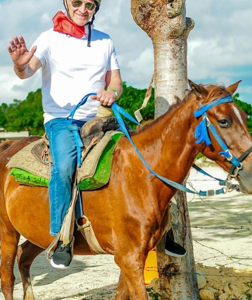 Happy tourist horseback riding on beach during Punta Cana tour adventure with taxiboat operator