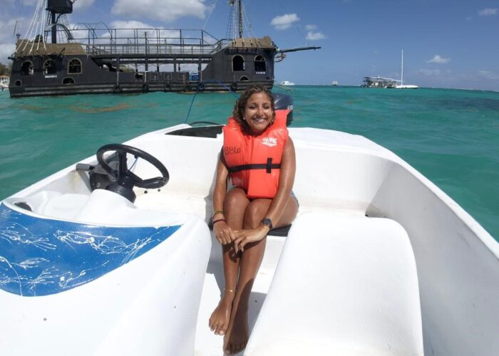Woman on taxiboat in Punta Cana with turquoise Caribbean waters and pirate ship tour boat in background
