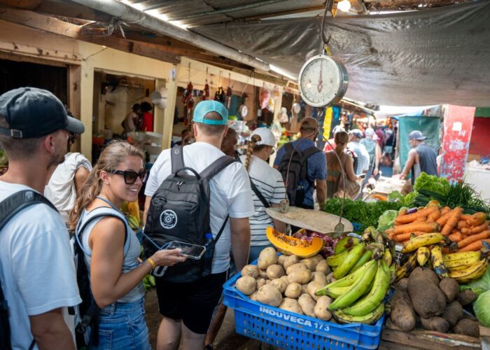 Tourists exploring local market at Punta Cana taxiboat tour stop with fresh tropical produce and local vendors