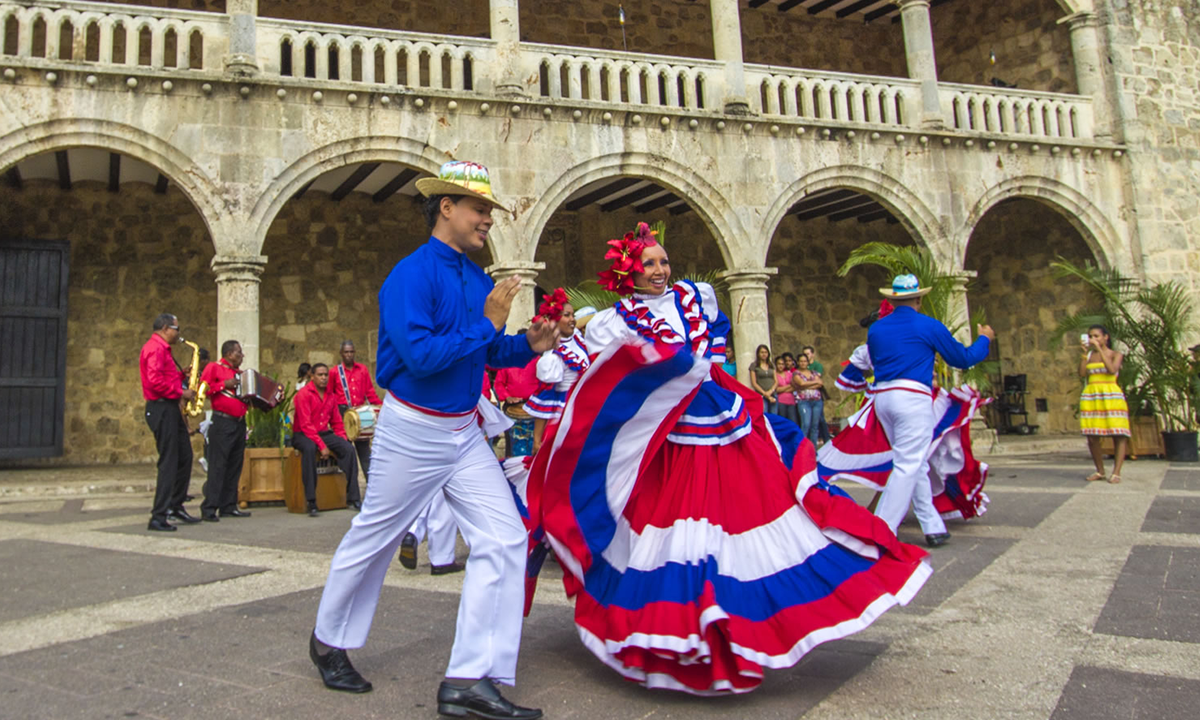 Traditional Dominican dancers performing at historic colonial architecture during Punta Cana cultural tour experience
