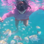 Child snorkeling in turquoise Punta Cana waters with tropical fish during taxiboat tour