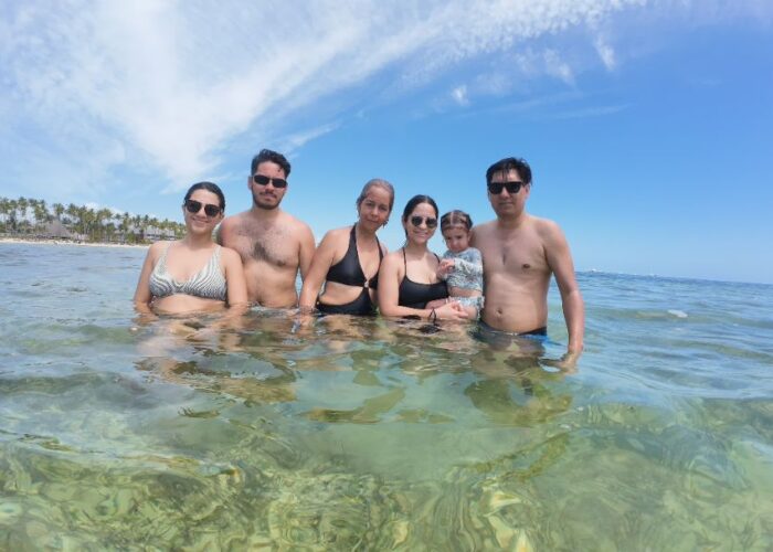 Family enjoying Fun Punta Cana Tours beach vacation in crystal clear turquoise waters with palm trees