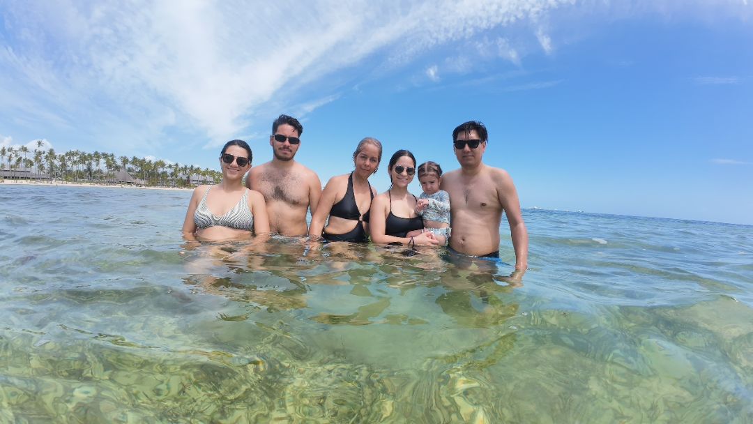 Family enjoying Fun Punta Cana Tours beach vacation in crystal clear turquoise waters with palm trees